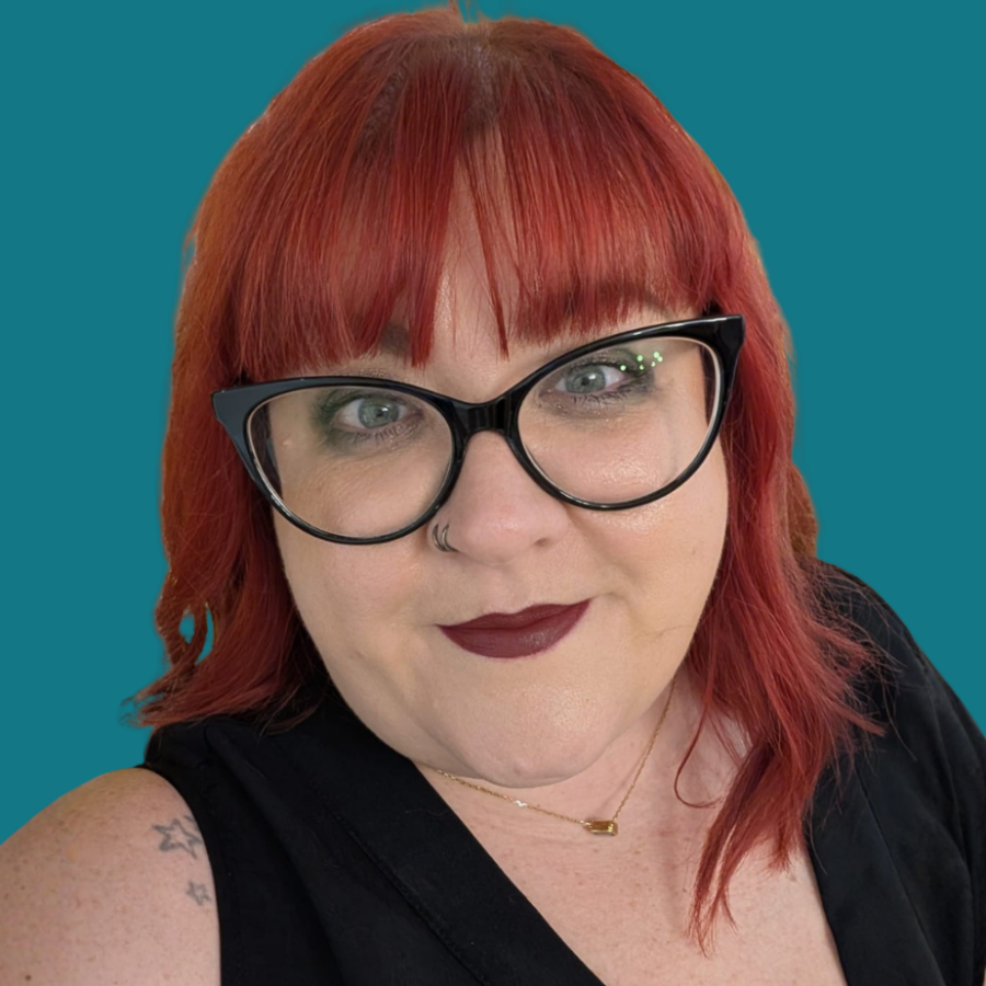 Person with red hair and glasses against a teal background